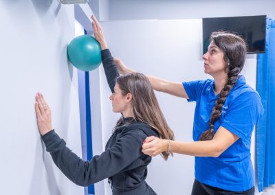 Istruttore guida un paziente in esercizi riabilitativi con una palla medica.