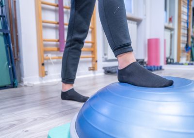 Paziente esegue esercizi di equilibrio su una mezza sfera BOSU.