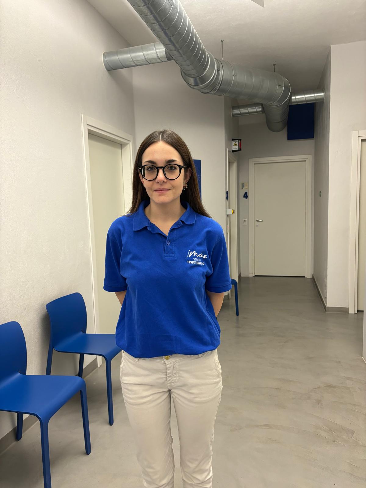 Ritratto di Cristina Faccin, terapista del team Studio Fisioterapico Mar, con polo blu e occhiali.