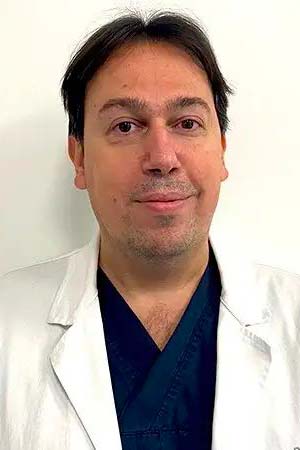 Ritratto della Dott.ssa Elena Colombo, specialista in ortopedia e fisiatria, sorridente in camice bianco davanti a un poster anatomico.